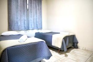 a room with two beds and a window at Casa Privativa em Sete Lagoas 35C in Sete Lagoas