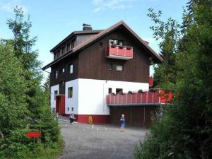 un grand bâtiment marron et blanc avec des personnes debout devant lui dans l'établissement Schlesierhaus, à Dachsberg im Schwarzwald