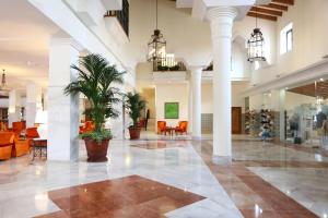 a lobby with potted plants and tables and chairs at Iberostar Selection Andalucia Playa in Chiclana de la Frontera