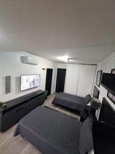 a living room with two beds and a flat screen tv at Frente Mar Santos 130 m2 in Santos