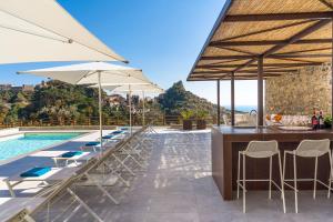a bar with chairs and umbrellas next to a pool at Villa Zagara in Savoca +32 photos