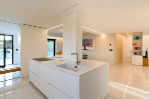 a white kitchen with a sink in the middle at Villa Zagara in Savoca