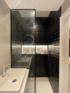 une salle de bain carrelée noire avec un lavabo et un miroir dans l'établissement Studio Zona Sul Laranjeiras RJ, à Rio de Janeiro