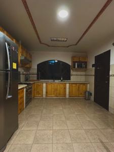 eine Küche mit Holzschränken und einem schwarzen Kühlschrank in der Unterkunft The Bunker in La Playa Bejarano