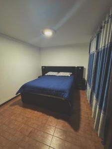 Schlafzimmer mit einem Bett mit blauer Bettwäsche und Vorhängen in der Unterkunft The Bunker in La Playa Bejarano