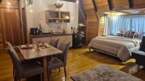 a bedroom with a bed and a table and a kitchen at Chalé Sol in Blumenau