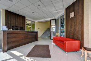 a lobby with a red couch and a staircase at Hotel Samaria in Šamorín