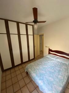 una camera da letto con un letto e un ventilatore a soffitto di Apartamento confortável no centro de Guarapari a Guarapari