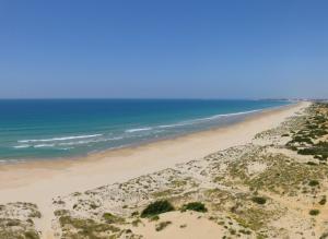 a beach with a sandy beach next to the ocean at Iberostar Selection Andalucia Playa in Chiclana de la Frontera
