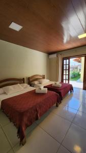 two beds in a room with a large window at Linda casa com excelente localização em Boipeba in Ilha de Boipeba