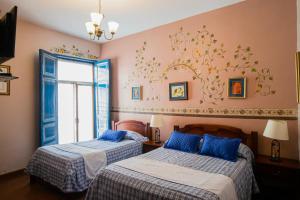 a bedroom with two beds and a window at Hotel Posada del Angel in Cuenca