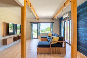 a living room with a couch and a tv at 新築! 一棟貸切 Sea Garden Ishigaki オーシャンビュー in Ishigaki Island