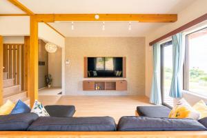 a living room with a couch and a tv at 新築! 一棟貸切 Sea Garden Ishigaki オーシャンビュー in Ishigaki Island