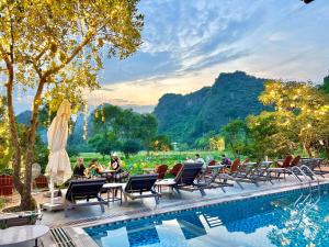 宁平Forest Sunset hostel的一群人坐在度假村的游泳池周围