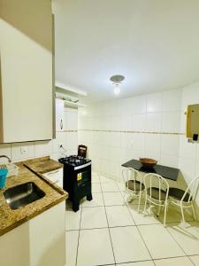 eine Küche mit Spüle und Tisch mit Stühlen in der Unterkunft Apartamento prainha rua da praia in Arraial do Cabo