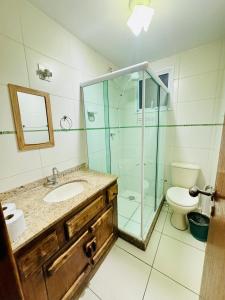 ein Badezimmer mit Waschbecken und Glasdusche in der Unterkunft Apartamento prainha rua da praia in Arraial do Cabo