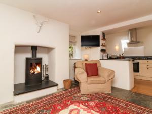 a living room with a chair and a fireplace at Old Maids Cottage in Ilfracombe