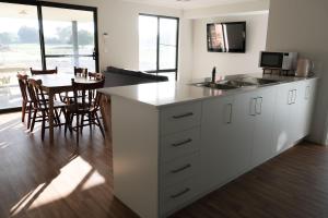 a kitchen with white cabinets and a table with chairs at Manjimup Gateway Hotel in Manjimup
