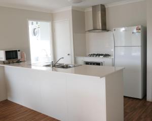 a white kitchen with a sink and a refrigerator at Manjimup Gateway Hotel in Manjimup