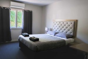 a bedroom with a large bed with a large headboard at Manjimup Gateway Hotel in Manjimup