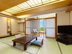 a living room with a table and a flat screen tv at KAMENOI HOTEL Aomori Makado in Noheji