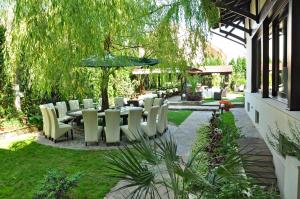 a patio with a table and chairs in a garden at Hotel Vila Class in Satu Mare