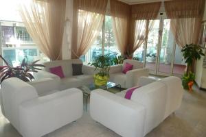 un soggiorno con divani bianchi e tavolo in vetro di Hotel Astra a Milano Marittima