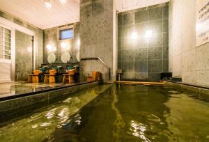 a pool of water in a room with tables and chairs at SUPERHOTEL Matsumoto Oshiroguchi in Matsumoto