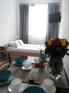 een tafel met een vaas met bloemen en een bed in een kamer bij Pod Trzynastką in Sandomierz
