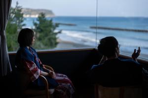 two women sitting in front of a window looking out at the ocean at Kaiyutei in Kawazu