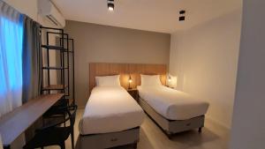 a hotel room with two beds and a desk and a desk at Casa Be Suites in Rosario