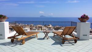 duas cadeiras e uma mesa numa varanda com o oceano em La Zagara Hotel em Lipari