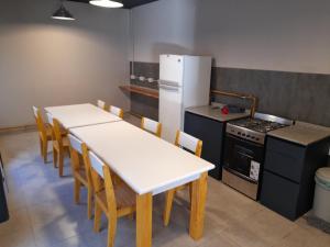 a kitchen with a table and chairs and a refrigerator at Guanaco Hostel in Puerto Madryn