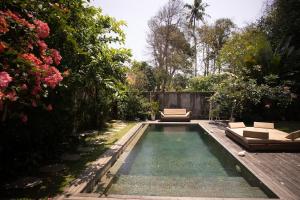 a swimming pool in a garden with chairs and flowers at Tropical Escape 2min Walk to Beach and Private Pool in Cemagi