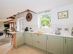 a kitchen with green cabinets and a window at Sylva Cottage in Shrewsbury