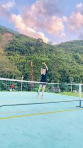a woman serving a tennis ball on a tennis court at Sapa Retreat Homestay & Restaurant in Lao Cai