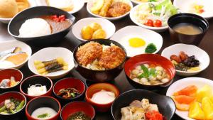 a table topped with bowls of different types of food at Dormy Inn Express Koriyama in Koriyama