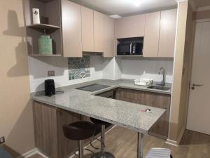 a kitchen with white cabinets and a counter with stools at Departamento en Ulriksen 2 in La Serena