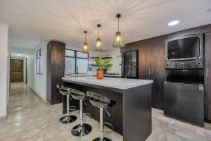 una cocina con isla con taburetes de bar en Urban 3rd floor Condo 3bed3bath 6guest max no elevator, en Envigado