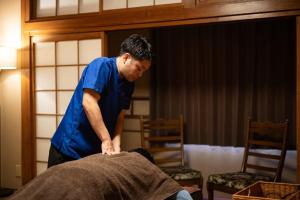 a man in blue shirt working on a bed at 民宿ととのい処ゑびすや in Unzen