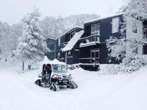 a snow vehicle is covered in snow in front of a building at Kilimanjaro Alpine Apartments in Falls Creek