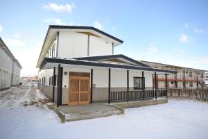 a white building with a brown door in the snow at Guesthouse TOU in Kushiro