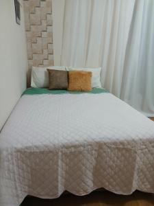 a white bed with two pillows on top of it at Casa Região Central! Próximo a Igreja, pontos turísticos 2 quartos in Aparecida