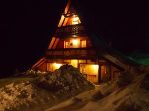 una cabaña de madera en la nieve por la noche en Holiday Home Tirol, en Vlašić