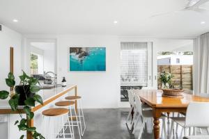 a kitchen and dining room with a wooden table and chairs at Sanctuary Spaces - Lomani Six in Byron Bay