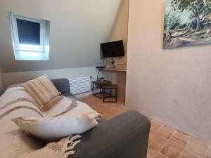 a living room with a couch and a television at Le Prieuré des Anges in Saint-Quentin-les-Anges