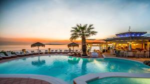 a pool at a resort with chairs and a palm tree at Delfino Blu Wellness Boutique Hotel in Agios Stefanos