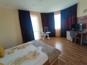 a hotel room with two beds and a television at Семеен Хотел Детелини in Primorsko