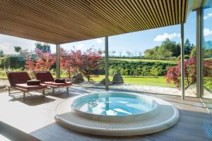 une terrasse avec un bain à remous au centre d'une maison dans l'établissement Hotel des Bains & Wellness Spa Nuxe, à Robertville