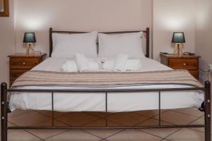 a bed with white sheets and pillows and two lamps at Homely Escape in Chios